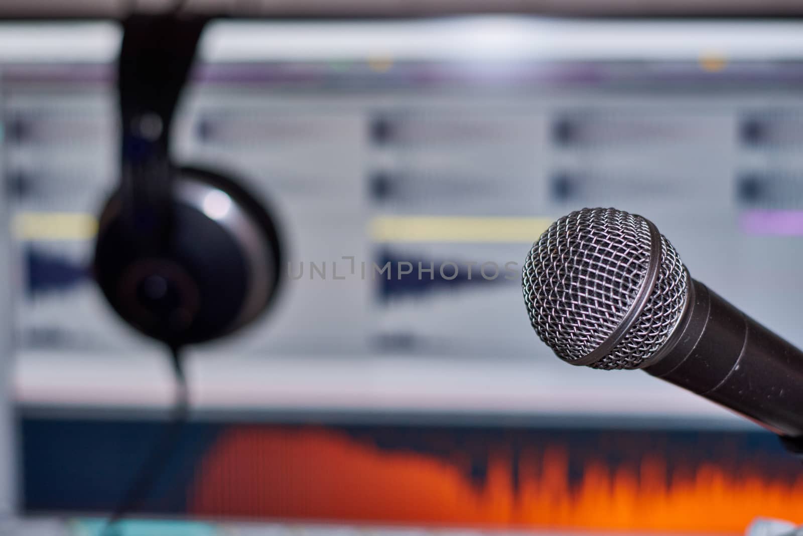Music production using computer, daw, headset and microphone. With audio waveforms in background.