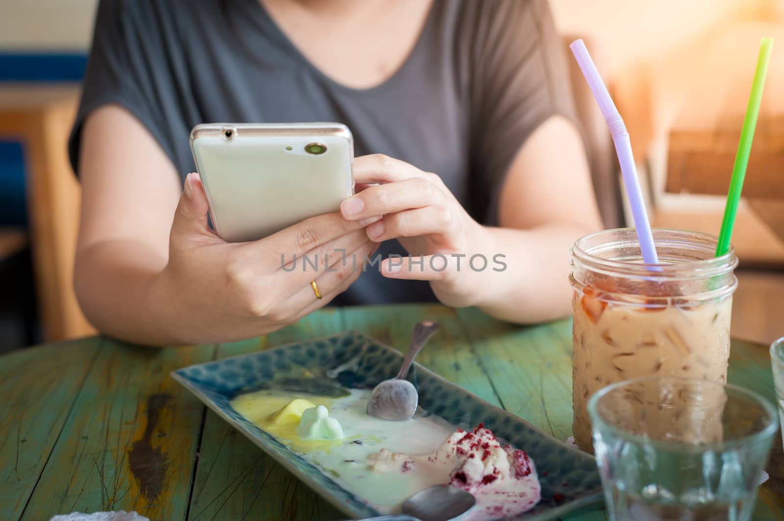 Afternoon scene of young woman using smartphone for social networking in cafe on weekend. Trendy lifestyle concept with technology.