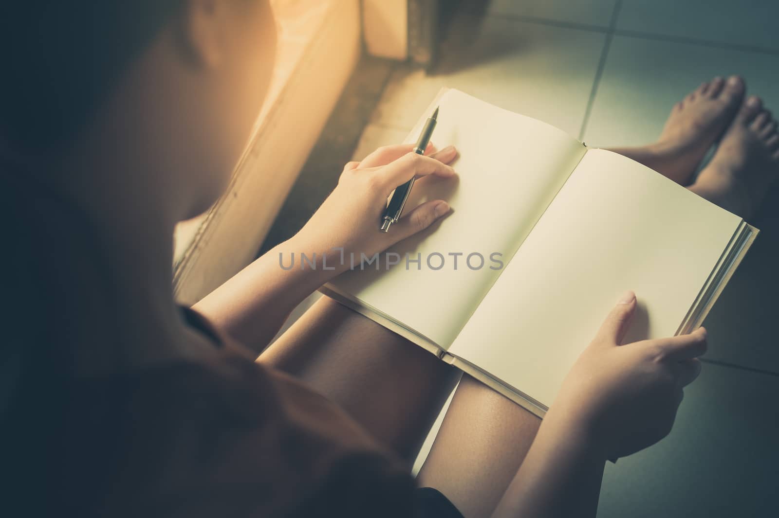 Young woman reading blank book while sitting beside window in morning time on weekend. Morning lifestyle on weekend concept with vintage filter effect
