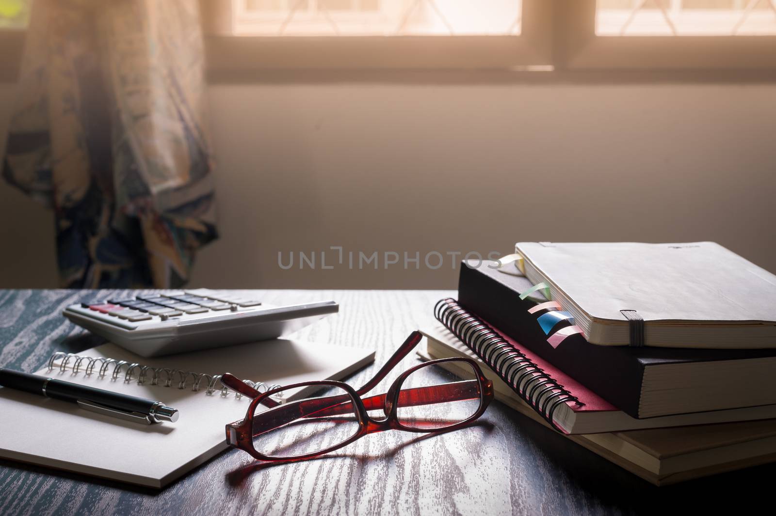 Glasses put down on table beside notebooks and pen in morning time on work day. Freelance business working concept