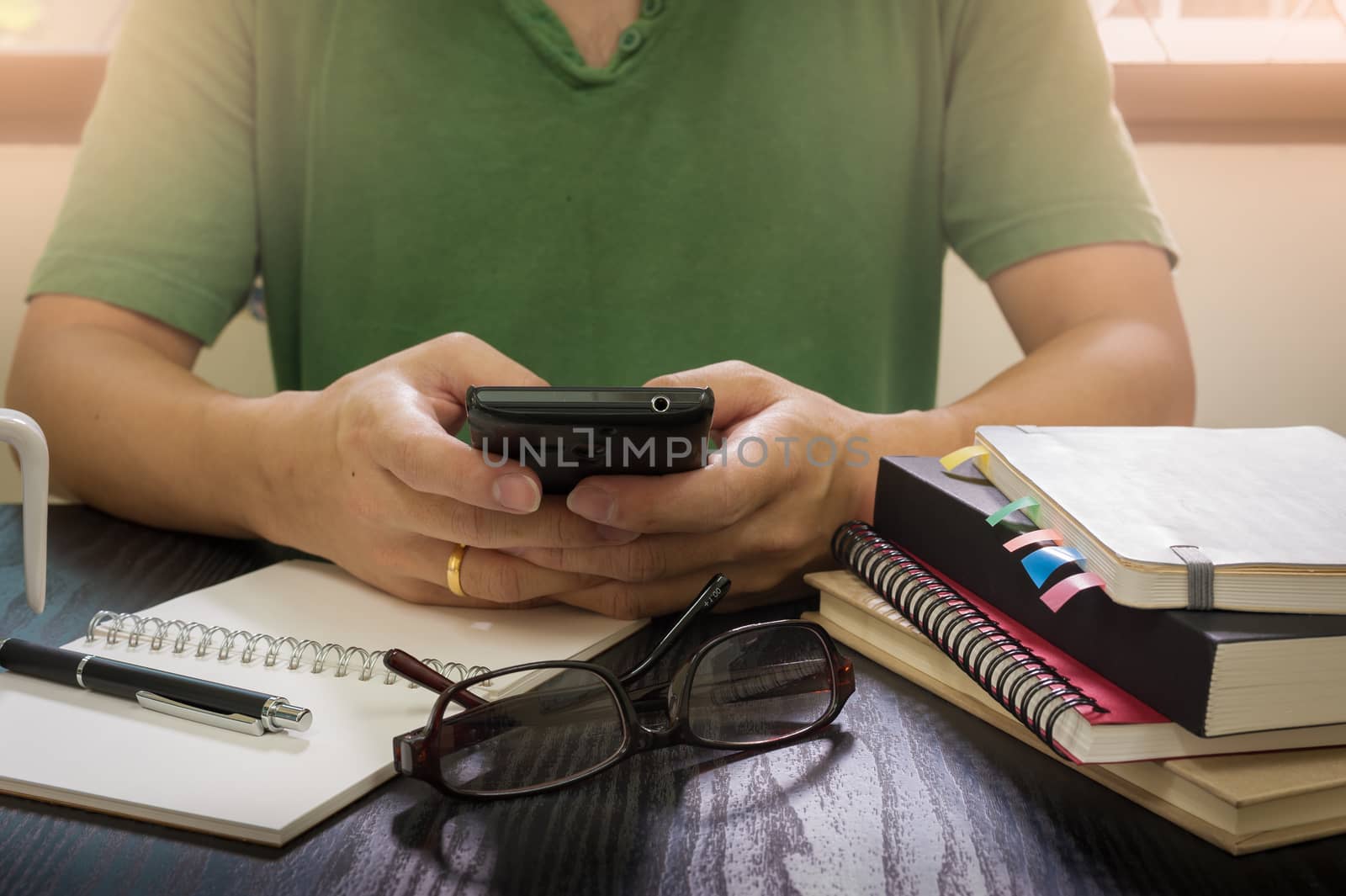 Young freelance man using smartphone for business on working desk in morning time on work day. Working at home concept