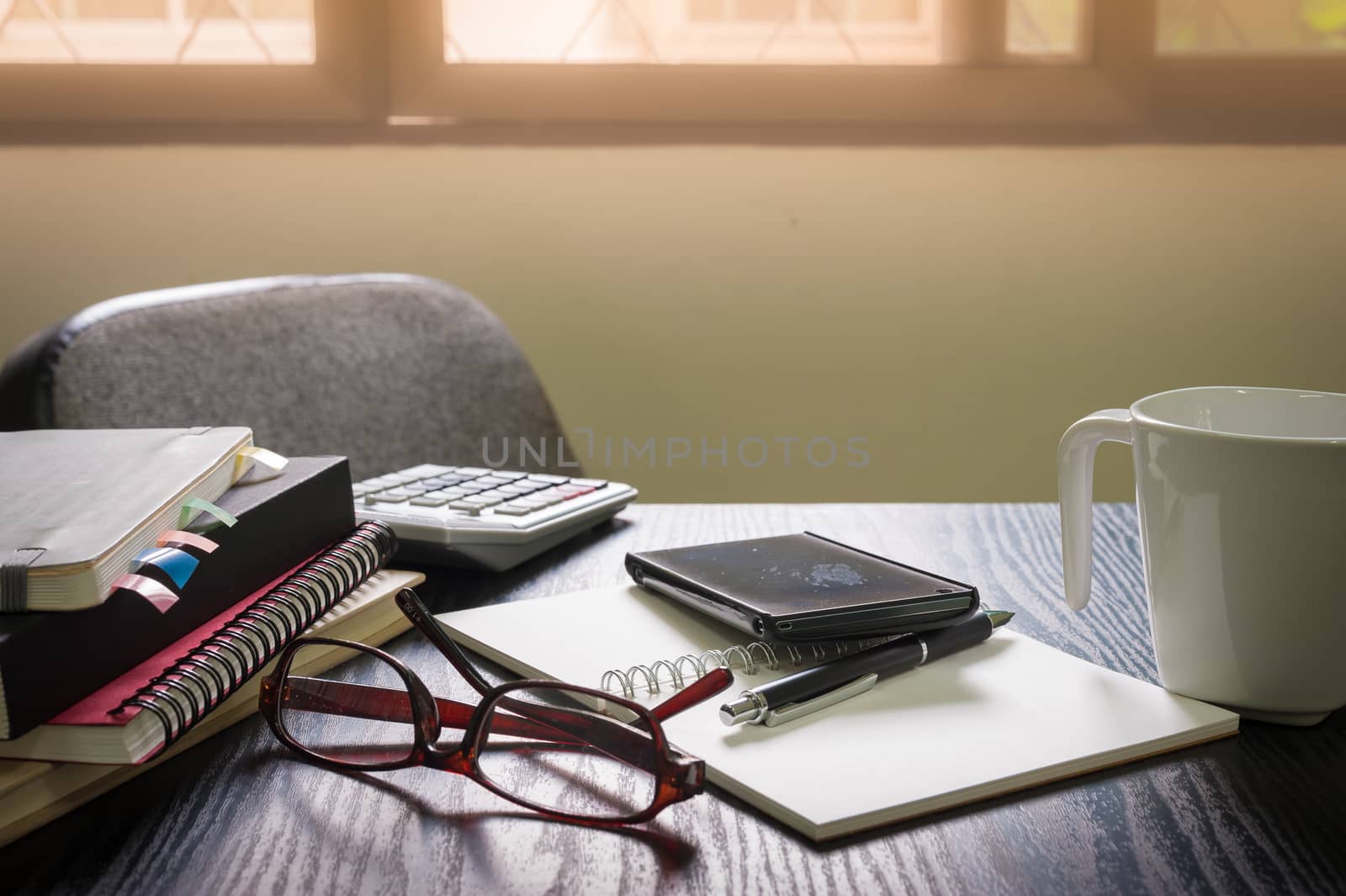 Smartphone put down on table beside notebooks and pen in morning time on work day. Business working at home concept