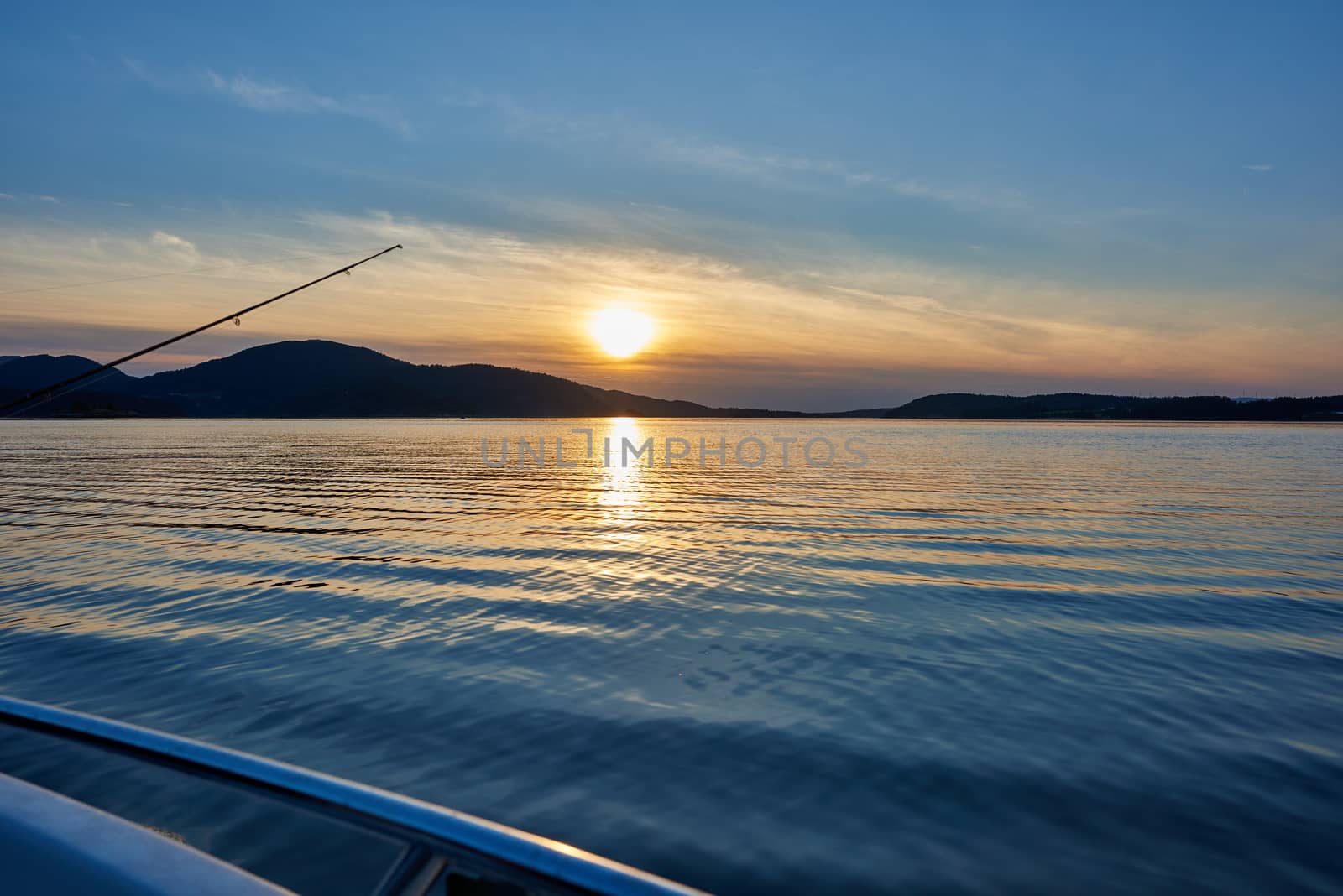 Fishing at dusk from a boat in sunset