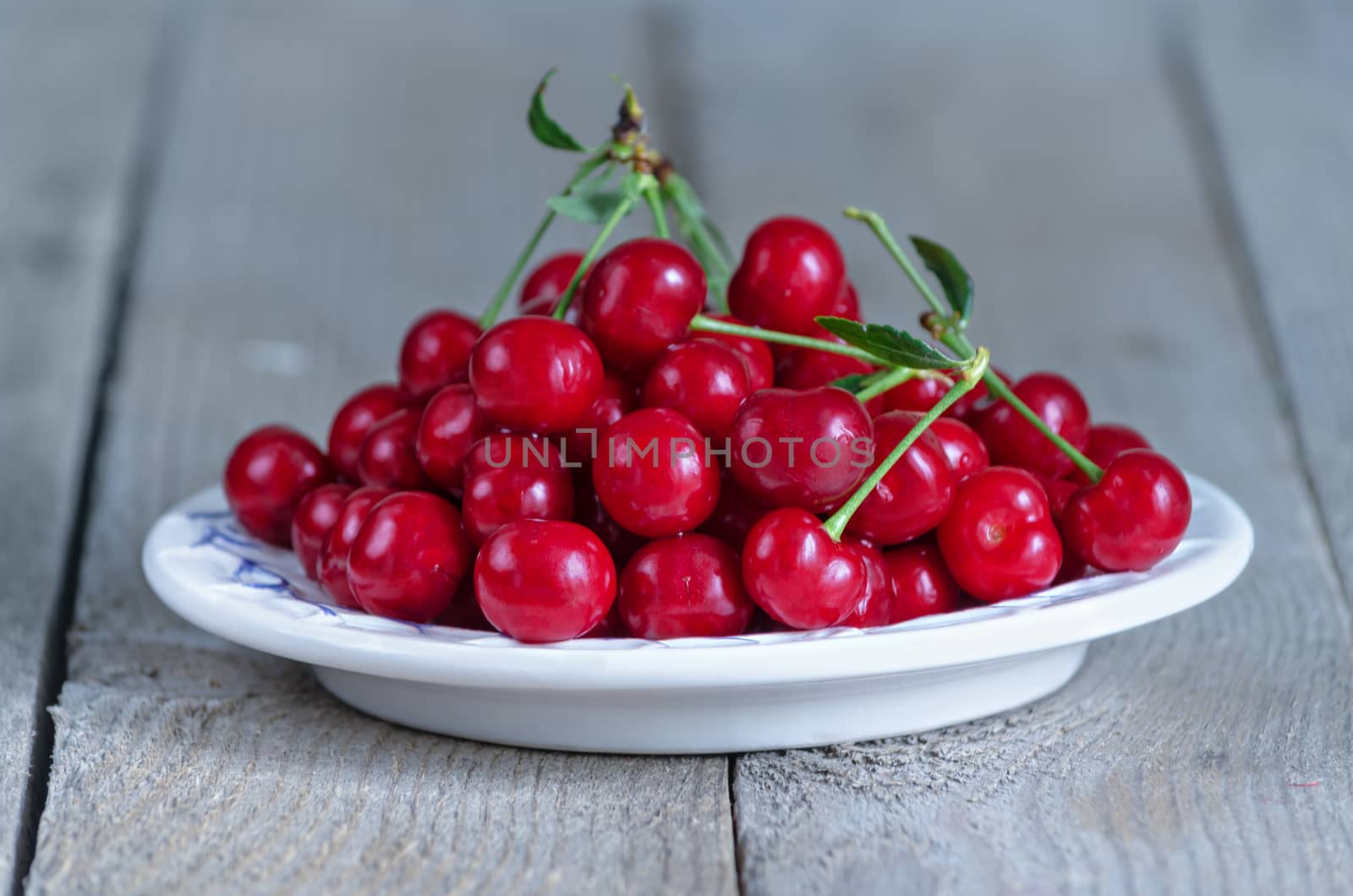 Cherry in plate on old boards, rustic style