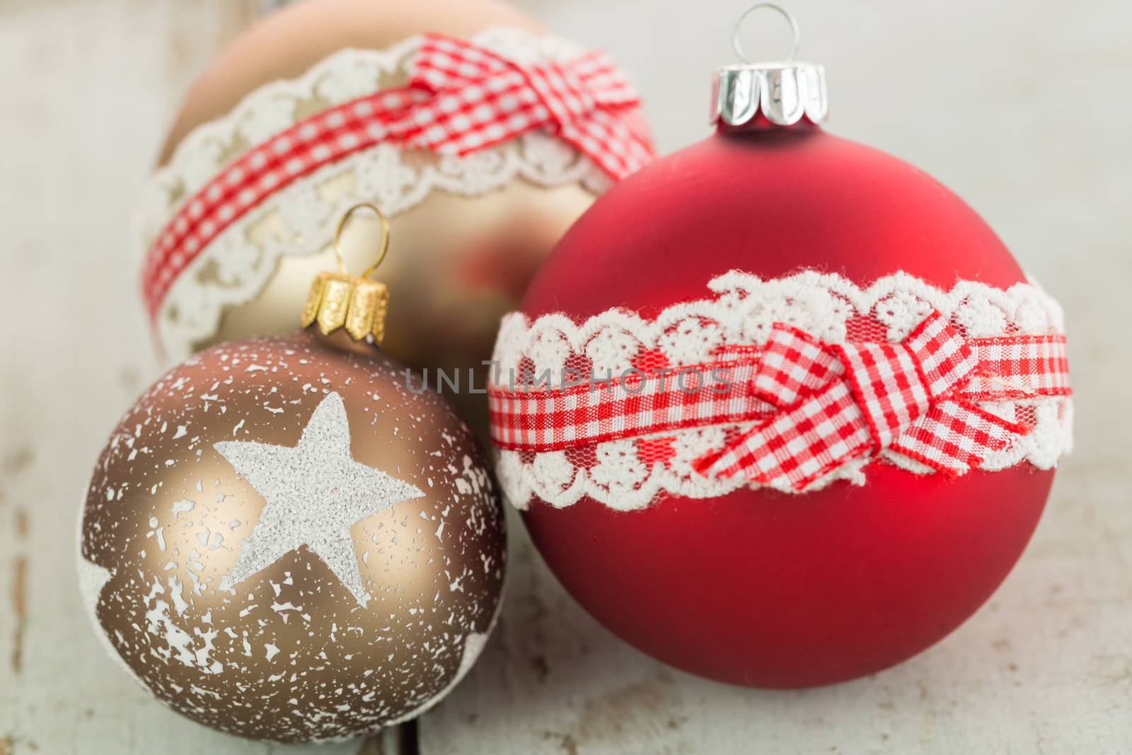 Three colorful decorated Christmas baubles on rustic wood with copy space to celebrate the Xmas holiday season