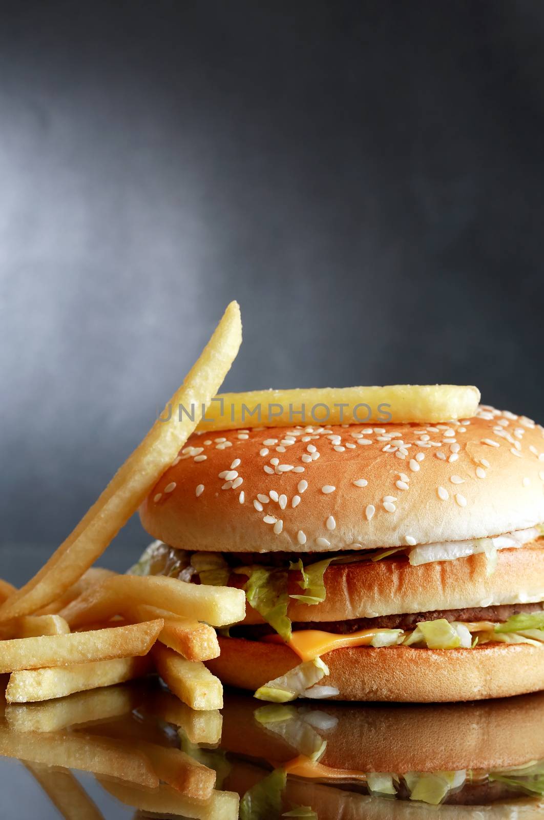 Closeup of hamburger near fried potatoes on dark background