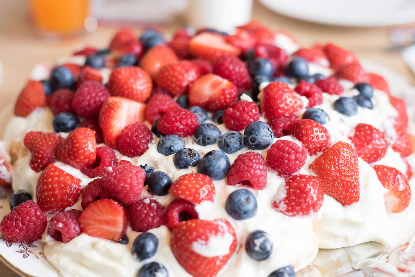 Pavlova cake with strawberry, blueberry, raspberry and whipped cream.