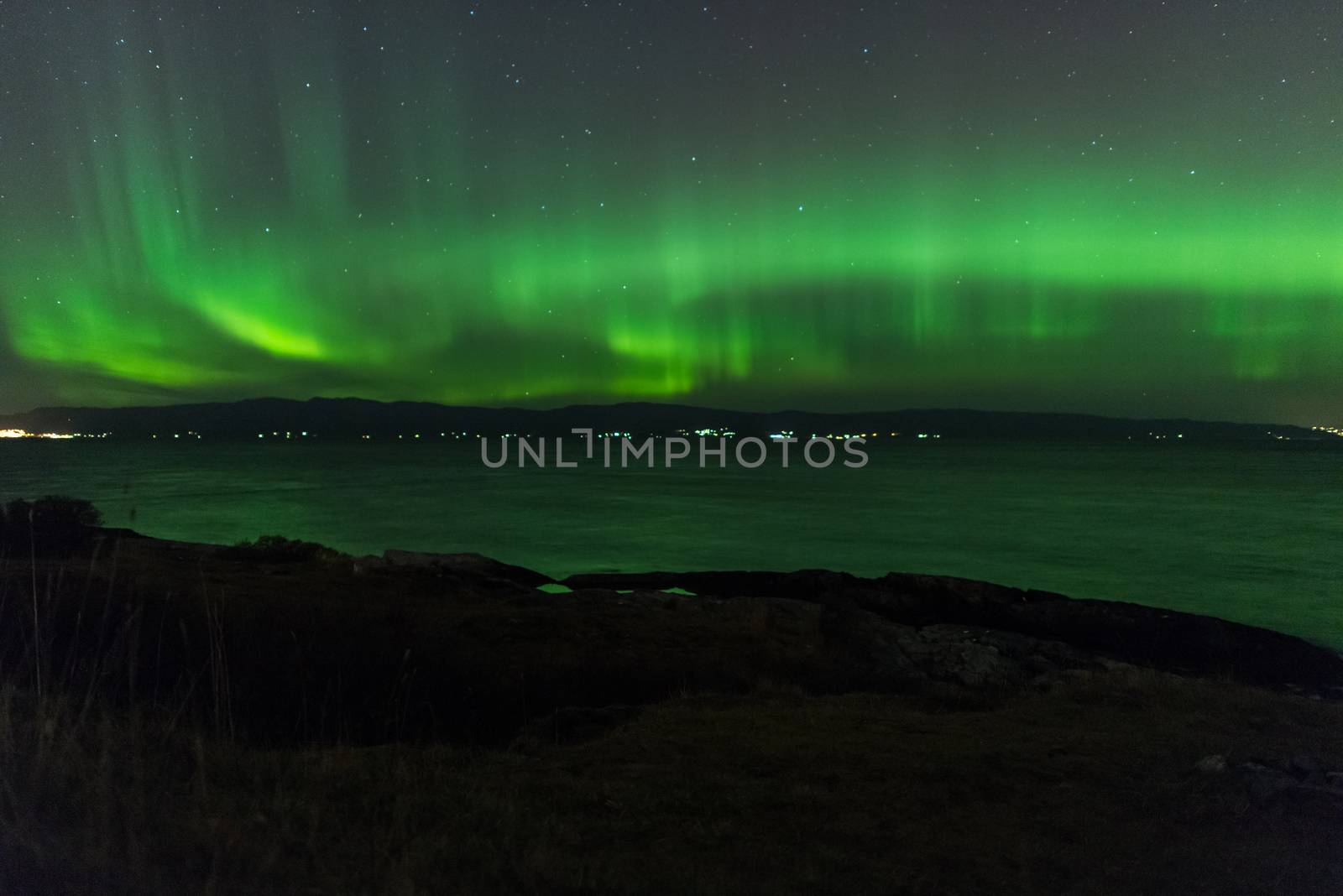 Northern Lights (Aurora Borealis) Over a lake in Norway at night.