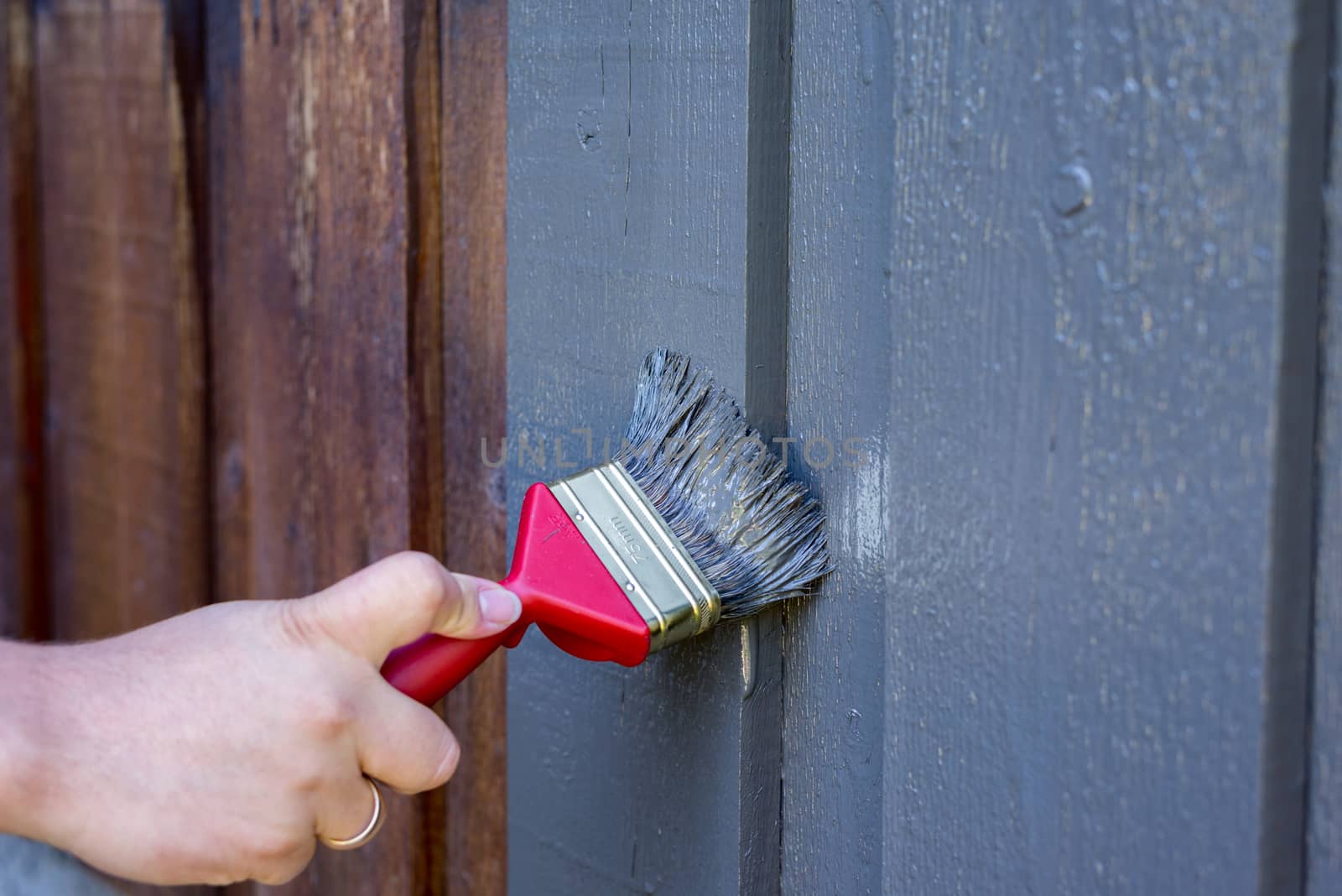 Painting a house exterior wall grey. Renovating building.