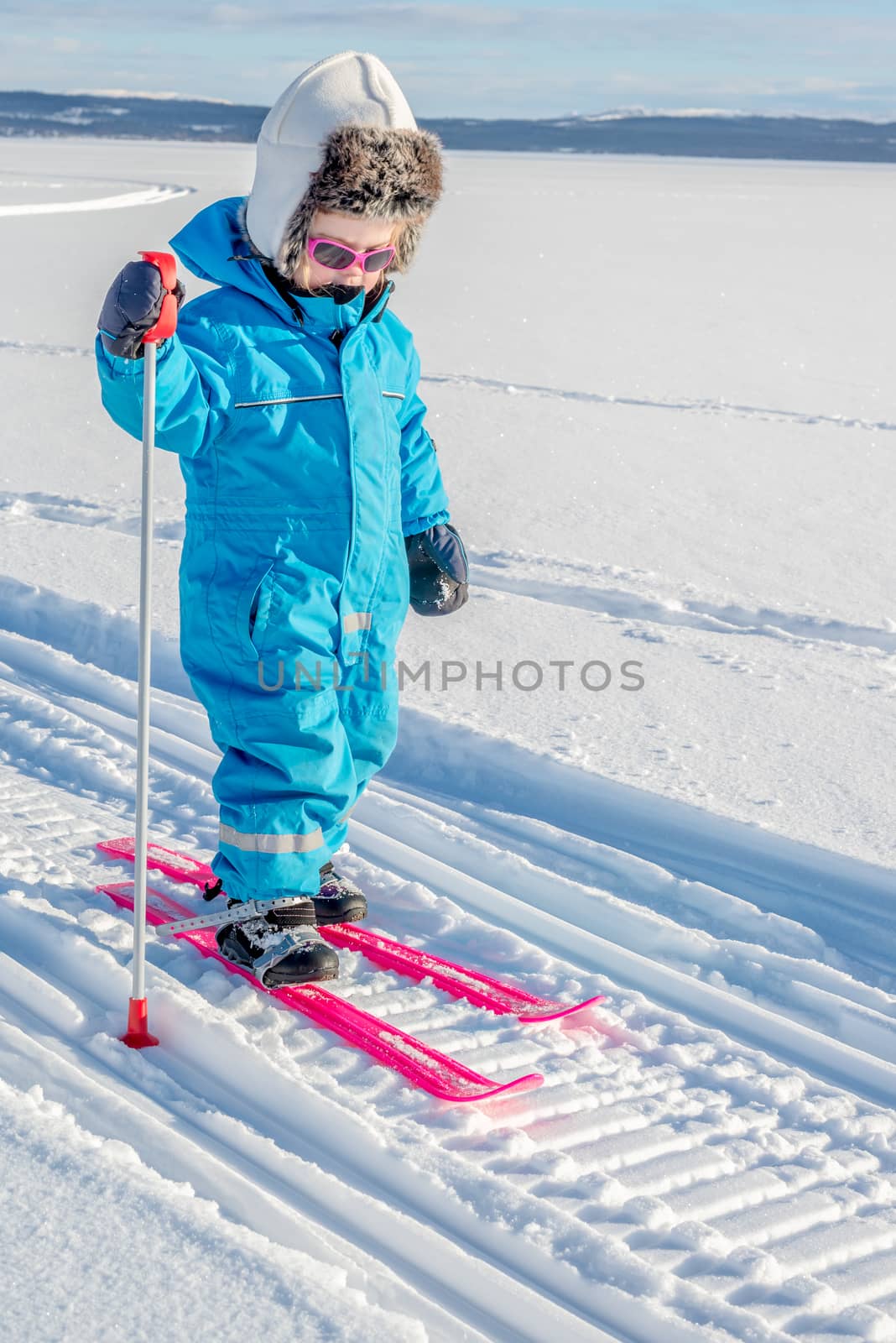 Young girl cross-country skiing. In snowmobile tracks.