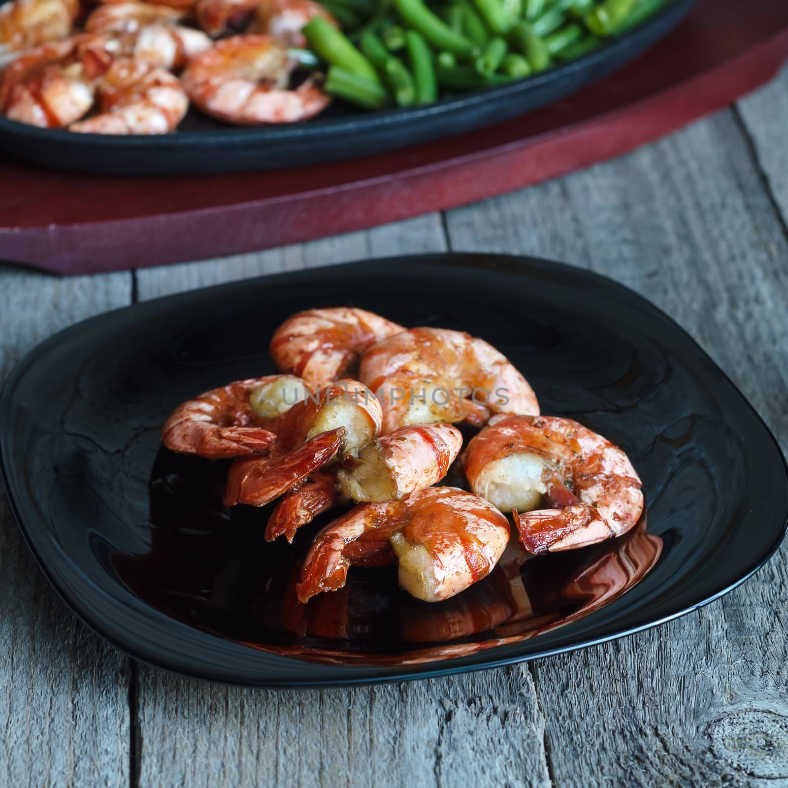 Dish with fried shrimp and green beans on wooden background
