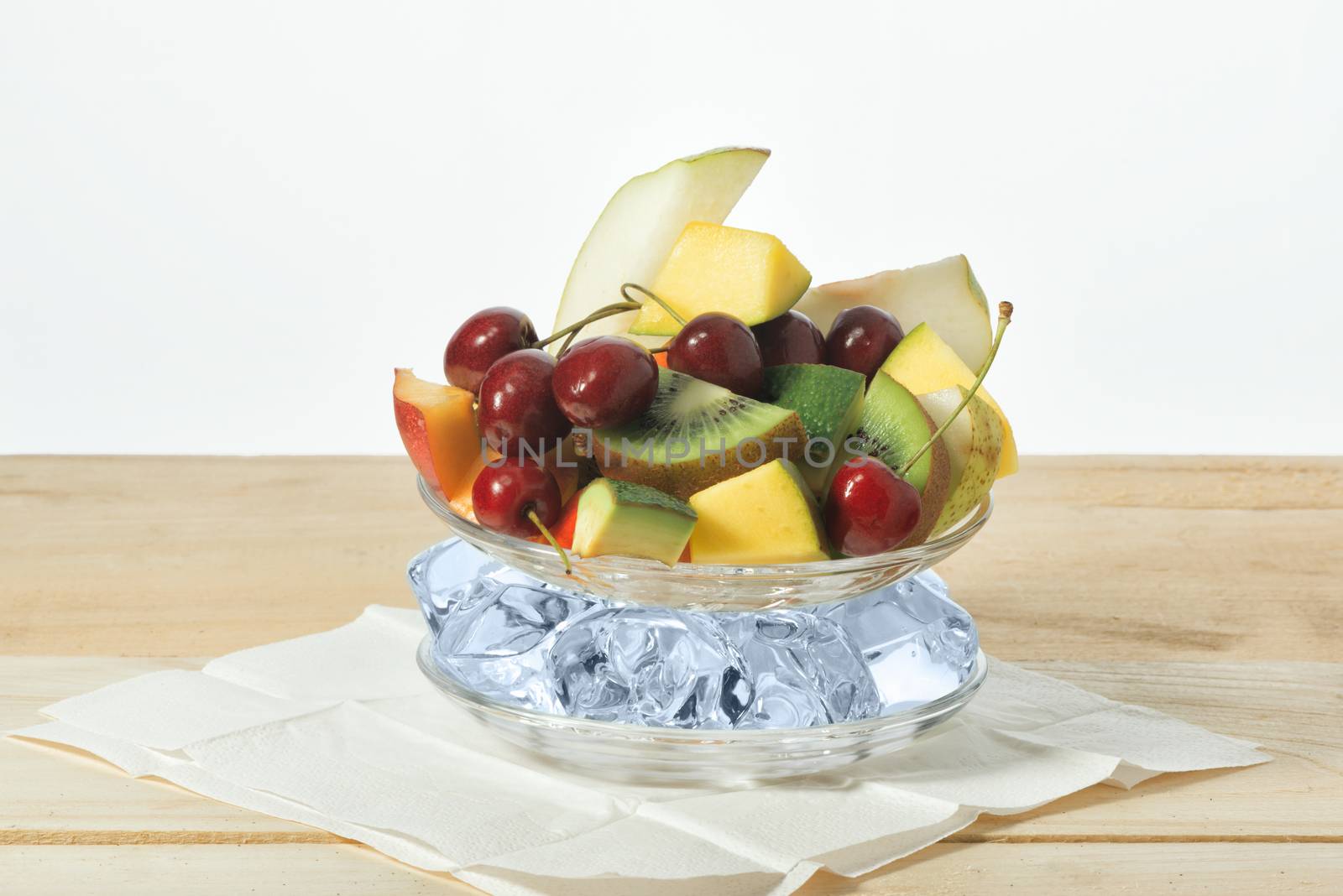 Slices of fruit, sweet cherry on a plate with ice on a surface from wooden boards