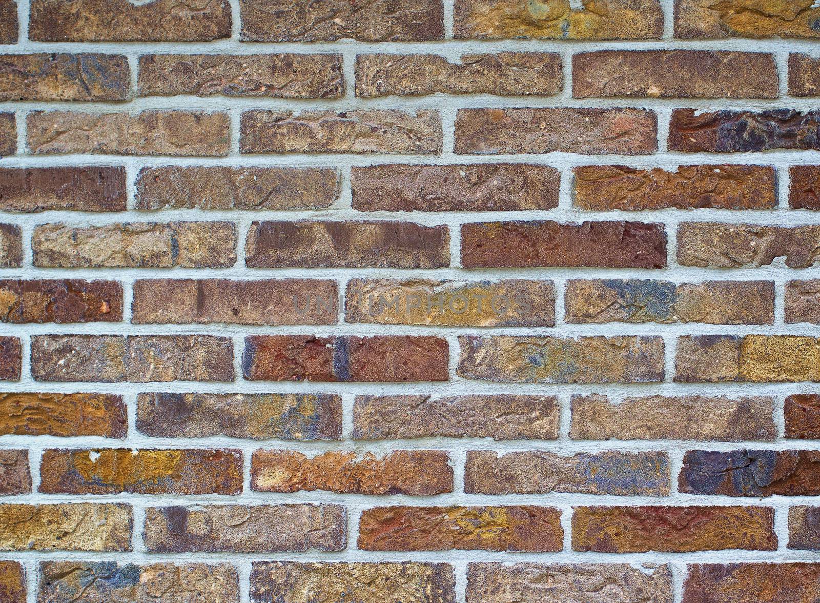 Background of Multi Colored Bricks with Cracked Surface and Concrete closeup Outdoors