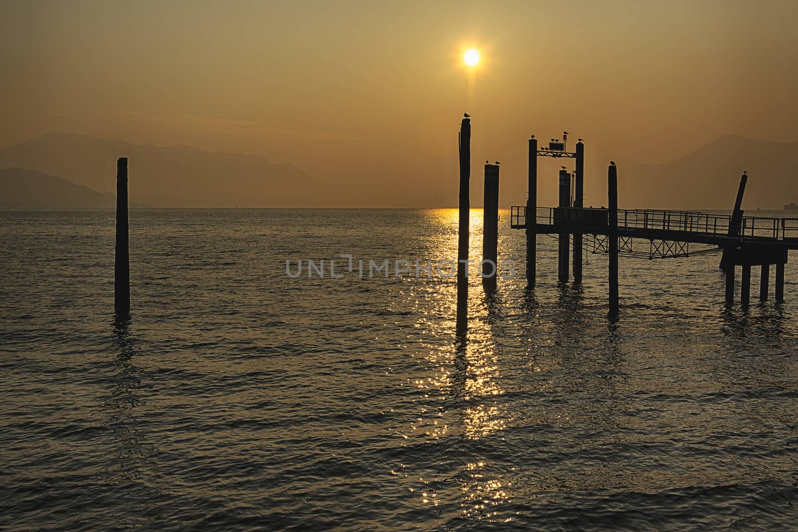 Pier at the sunset on the Major Lake in a wonderful contest with mountains at the horizon 