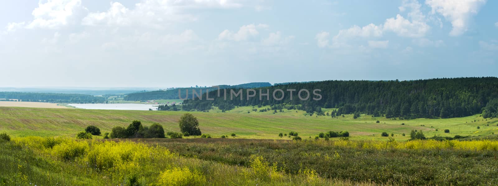 Wonderful summer panoramic view of fields with lake