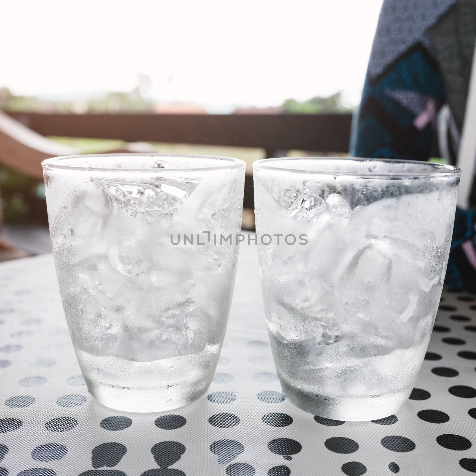 Glasses with ice cubes on black dot background table by nopparats