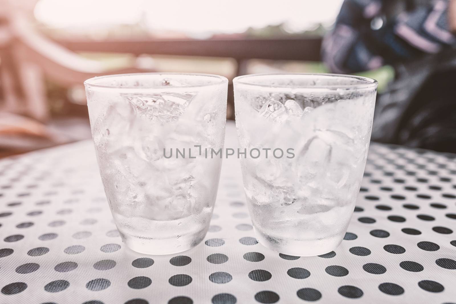 Glasses with ice cubes on black dot background table by nopparats