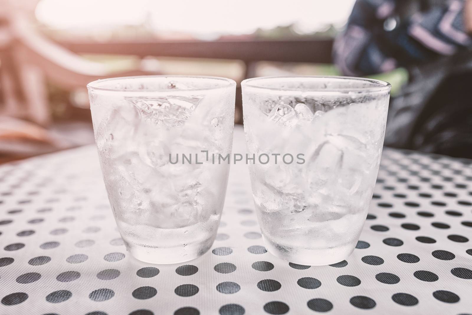 Glasses with ice cubes on black dot background table .