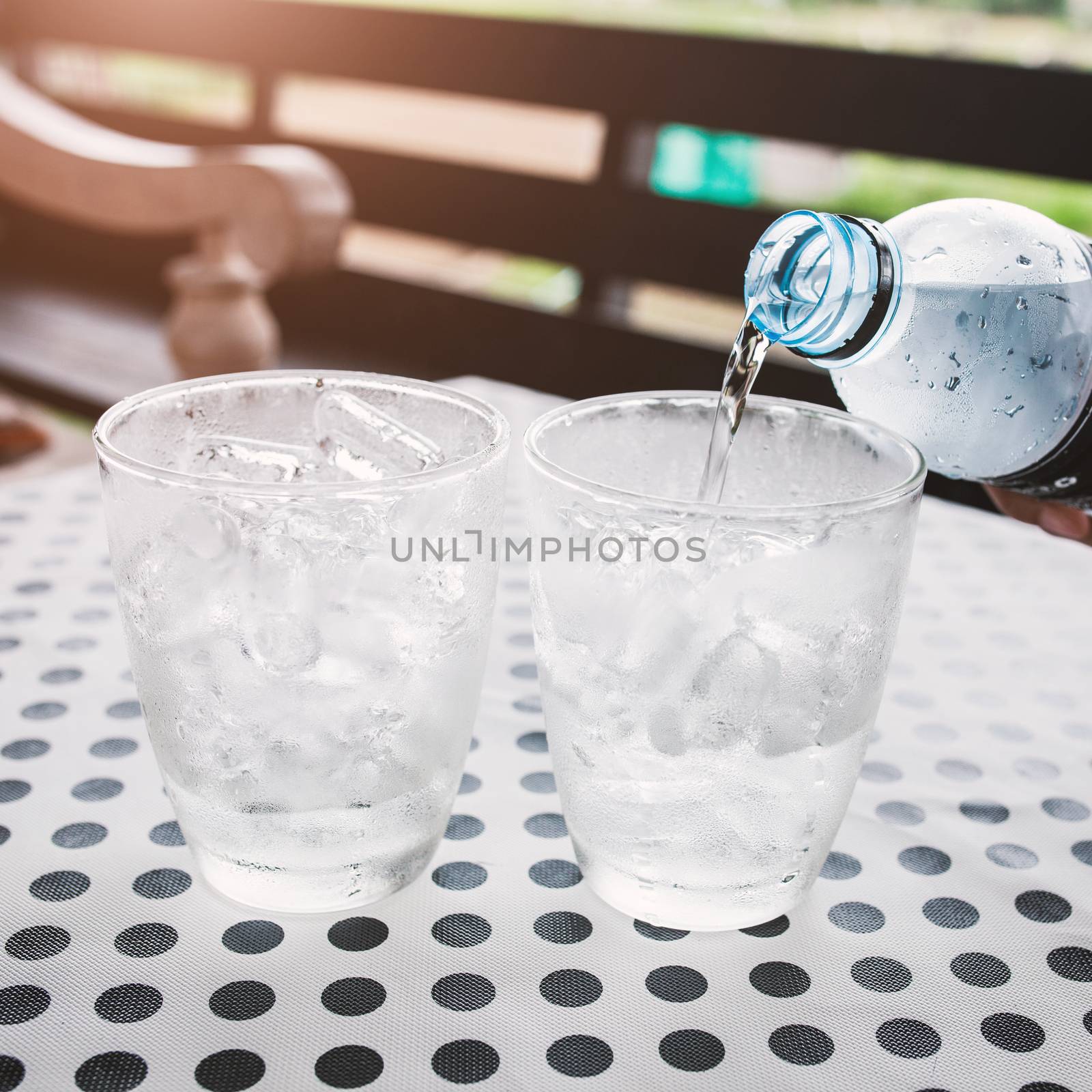 Glasses with ice cubes on black dot background table .
