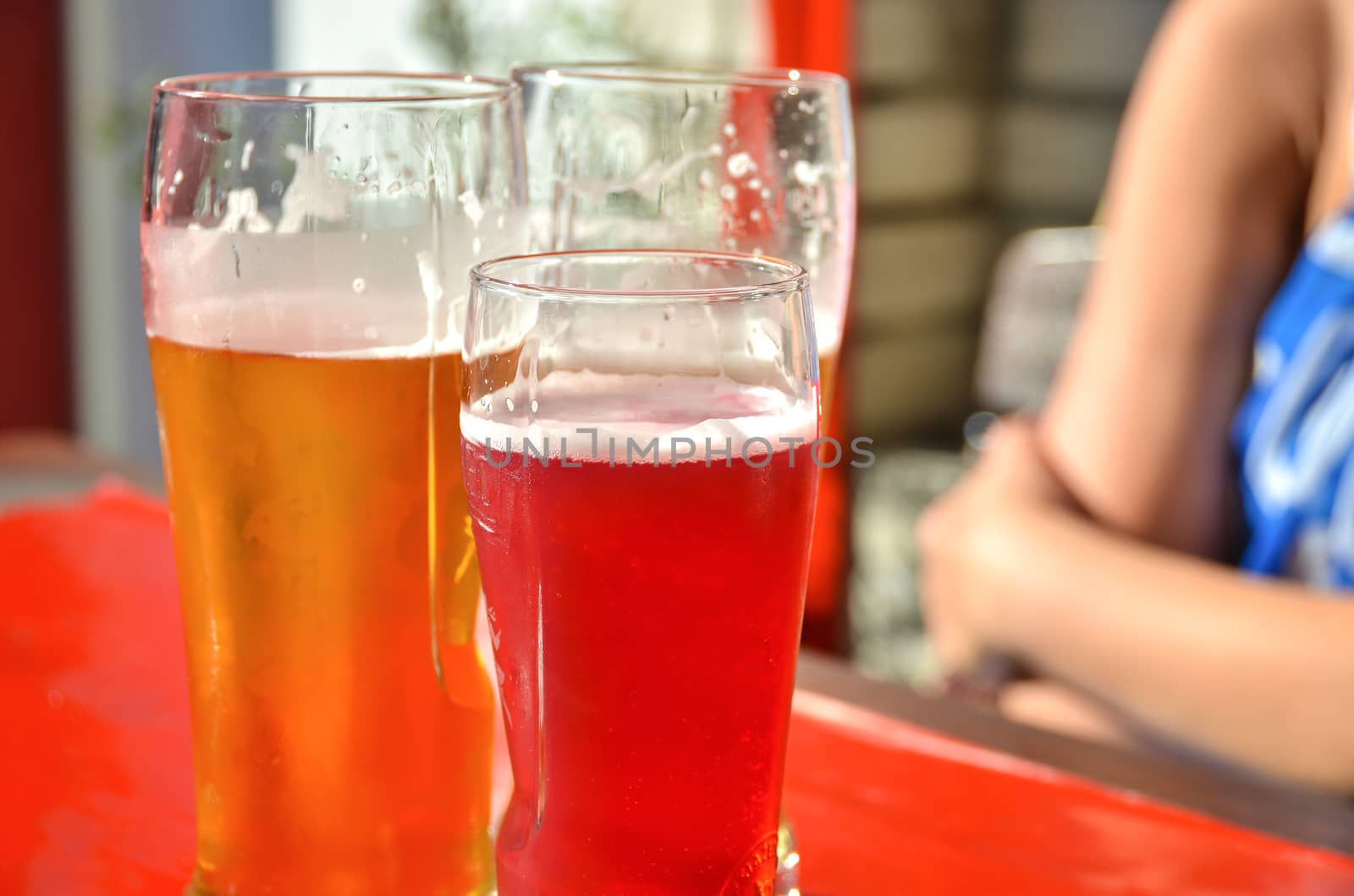 Three glasses with beer, one beer is with juice mixed.