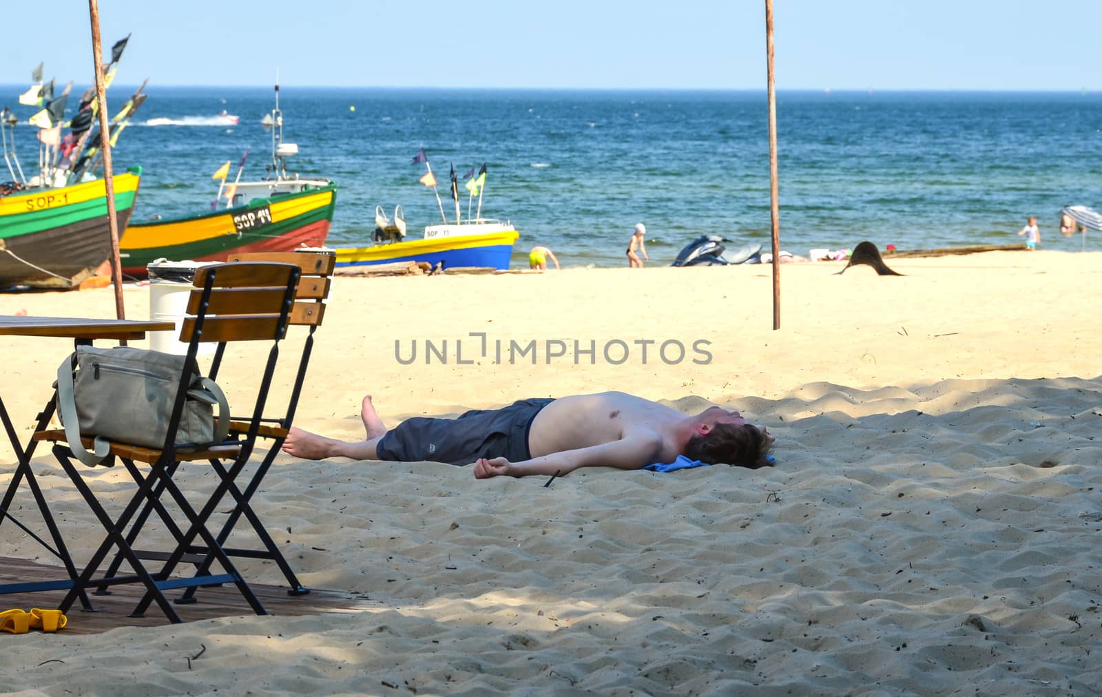 Sopot-Poland June-2016, Tired man lying down on sand in shadow spot on the beach at Baltic sea.