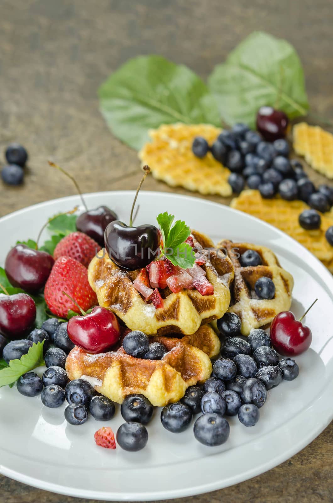 Homemade waffles with strawberry , blueberry and cherry on white plate