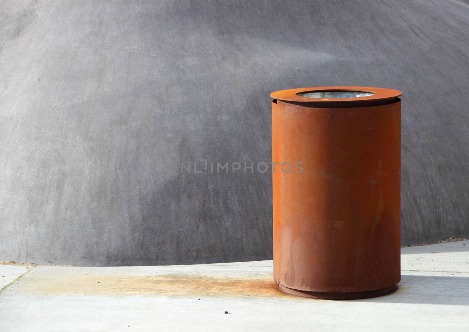 Garbage Can of Rusty Iron with Shadow on Concrete Surface