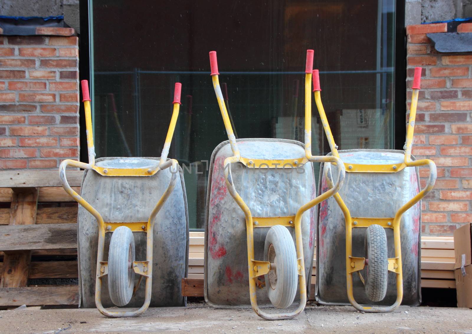 Three Metal Wheelbarrows with Red Handles at Construction Site Closeup