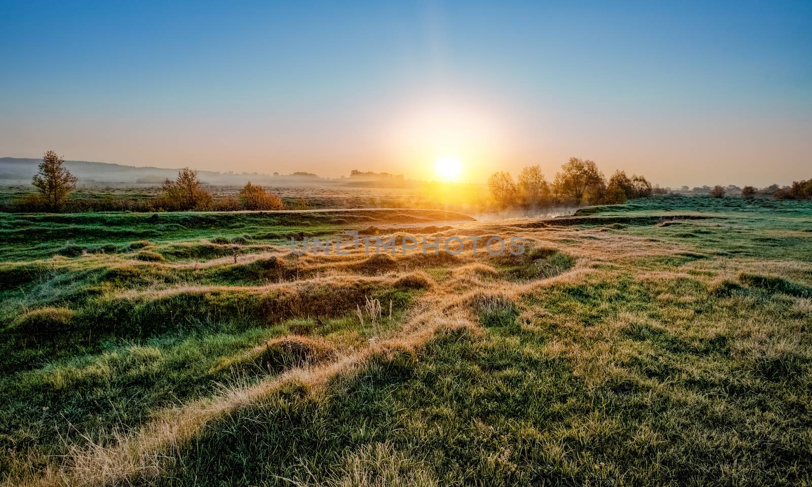 frosty morning sunrise over the river and a field
