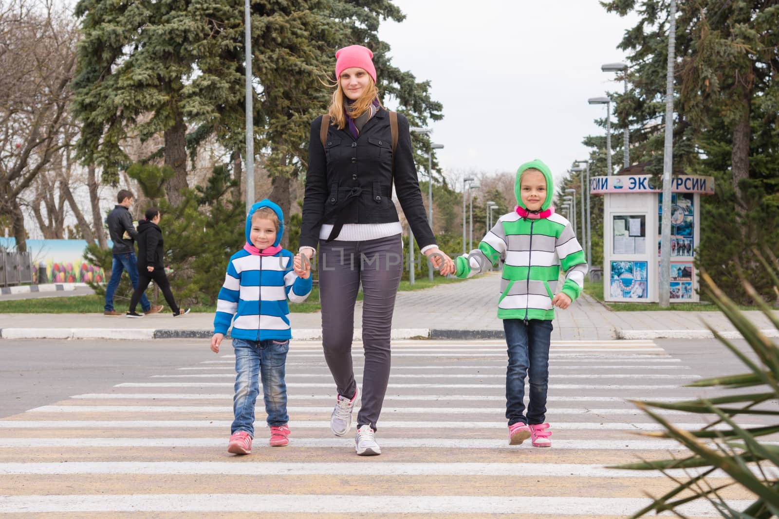 Anapa, Russia - March 9, 2016: a young mother with two daughters cross the road at a pedestrian crossing