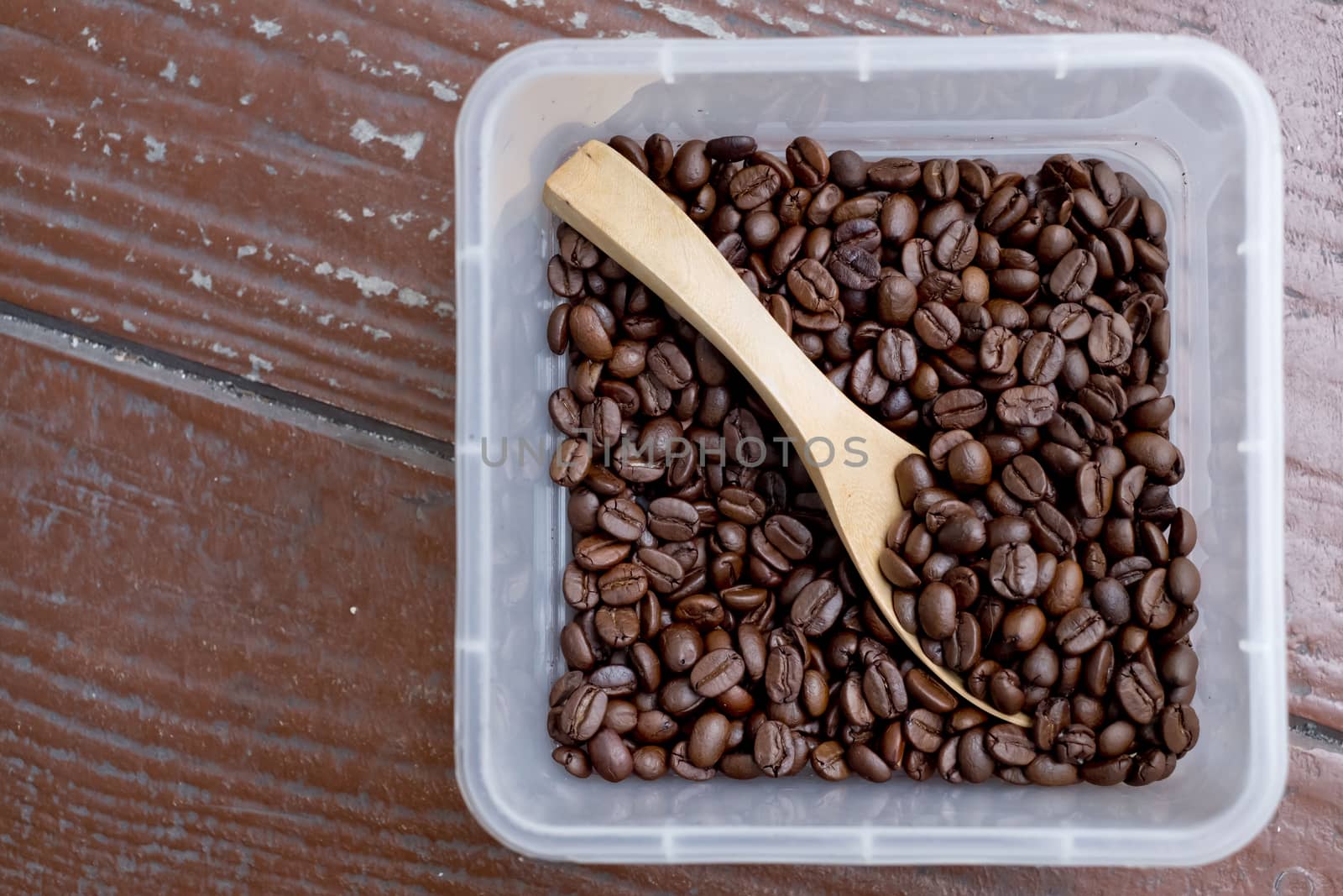 Coffee beans, square shaped box with wooden spoon. Wooden surface.