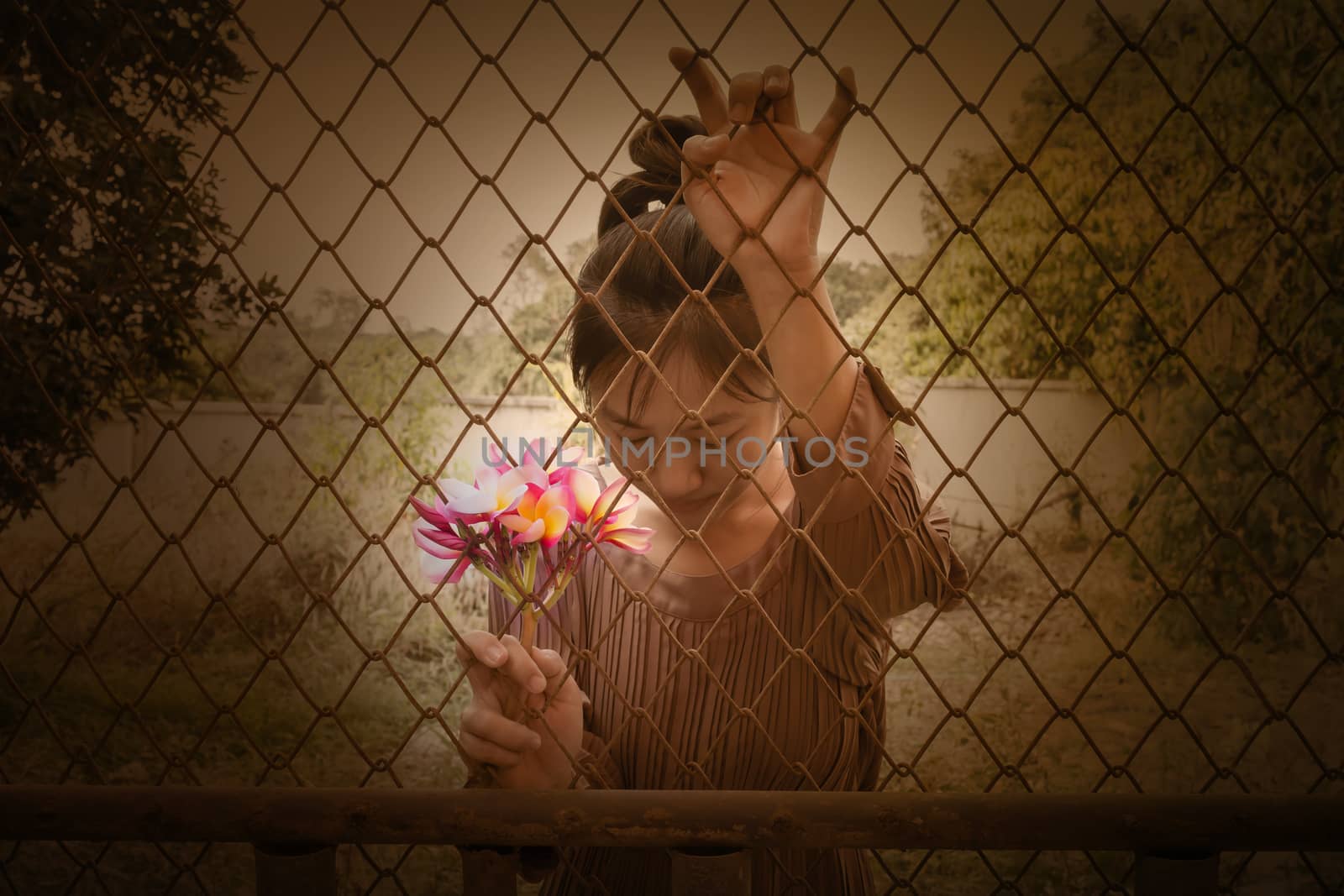 Women and bunch of pink flowers frangipani in hand behind iron bar
