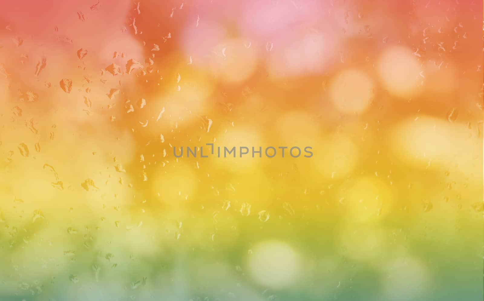 Abstract blurred background rain drop on glass mirror in fresh colourful summer orange pink and green bokeh