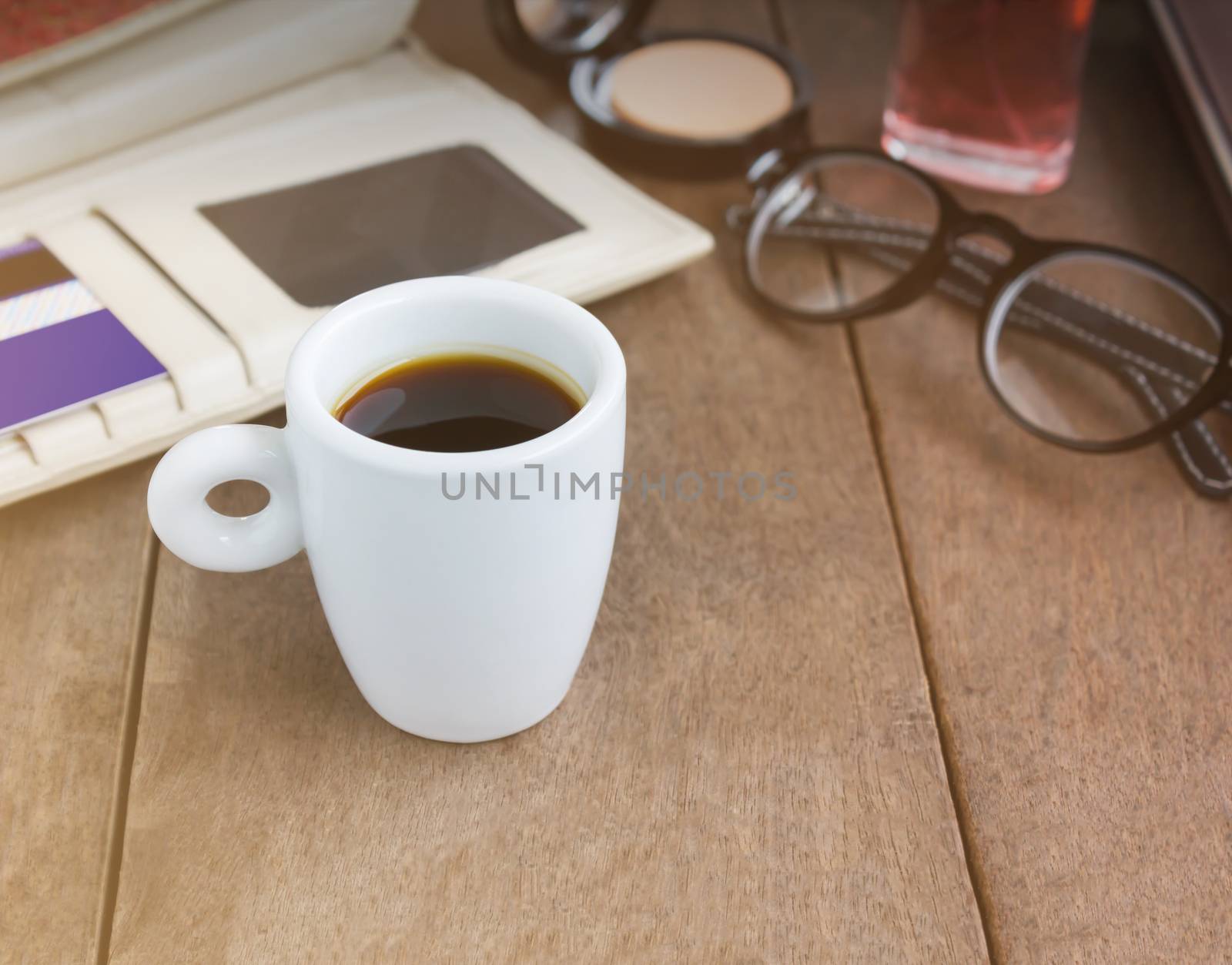 White cup hot black coffee on wood table with working women things