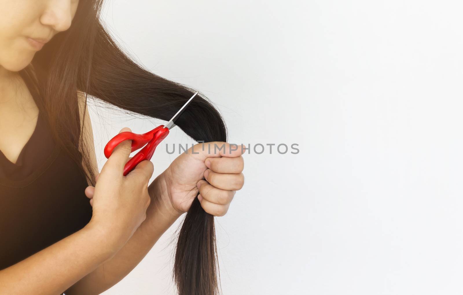 Focused to lady hand catch scissors cutting long hair on plain background and copy space
