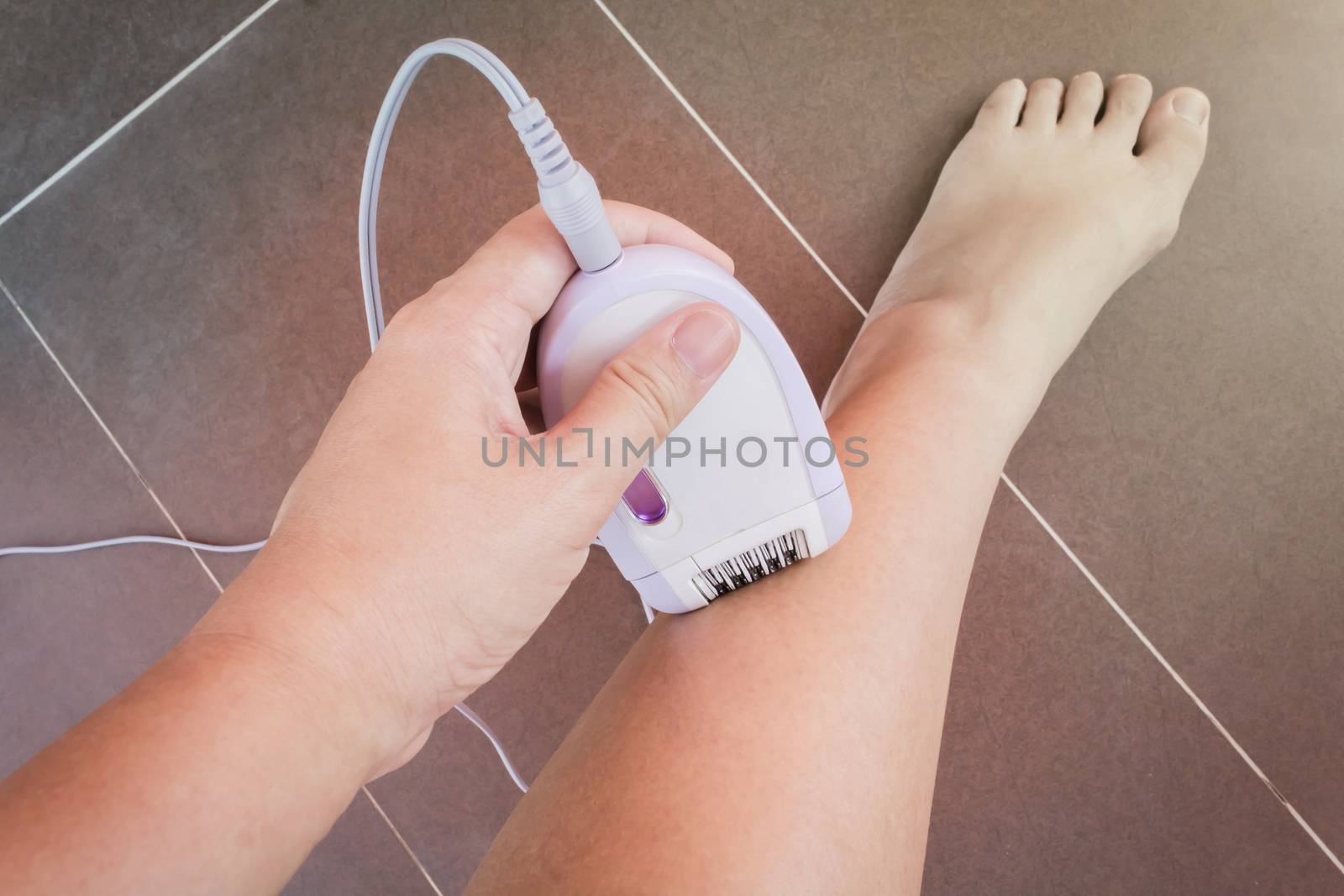Lady hand shaving leg hair by hair removal machine
