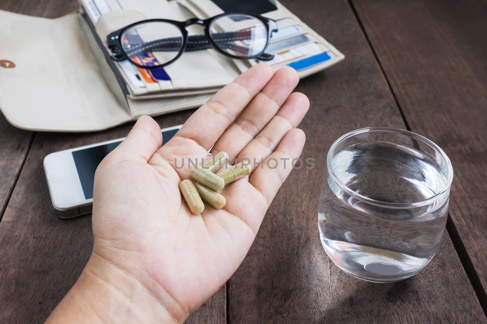 Herb medicine on hand and glass of water on work table