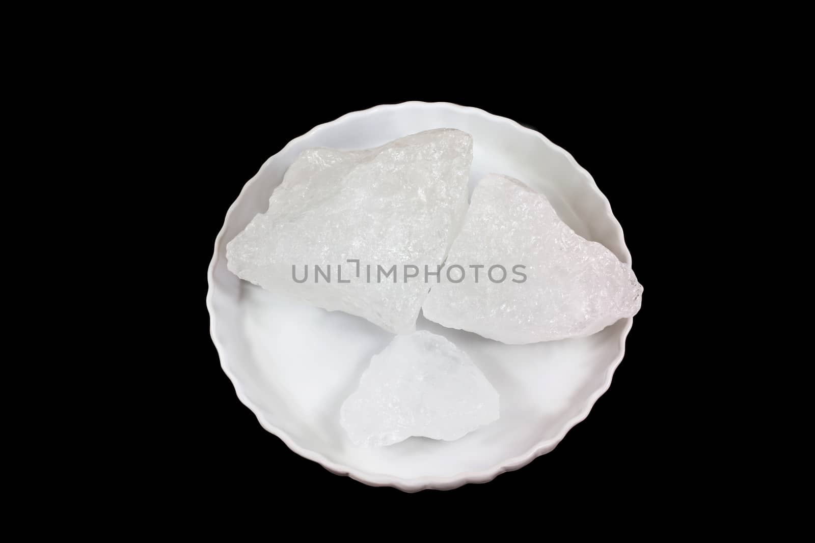 Isolatedtop view of three chunk of alum on white plate  on black background