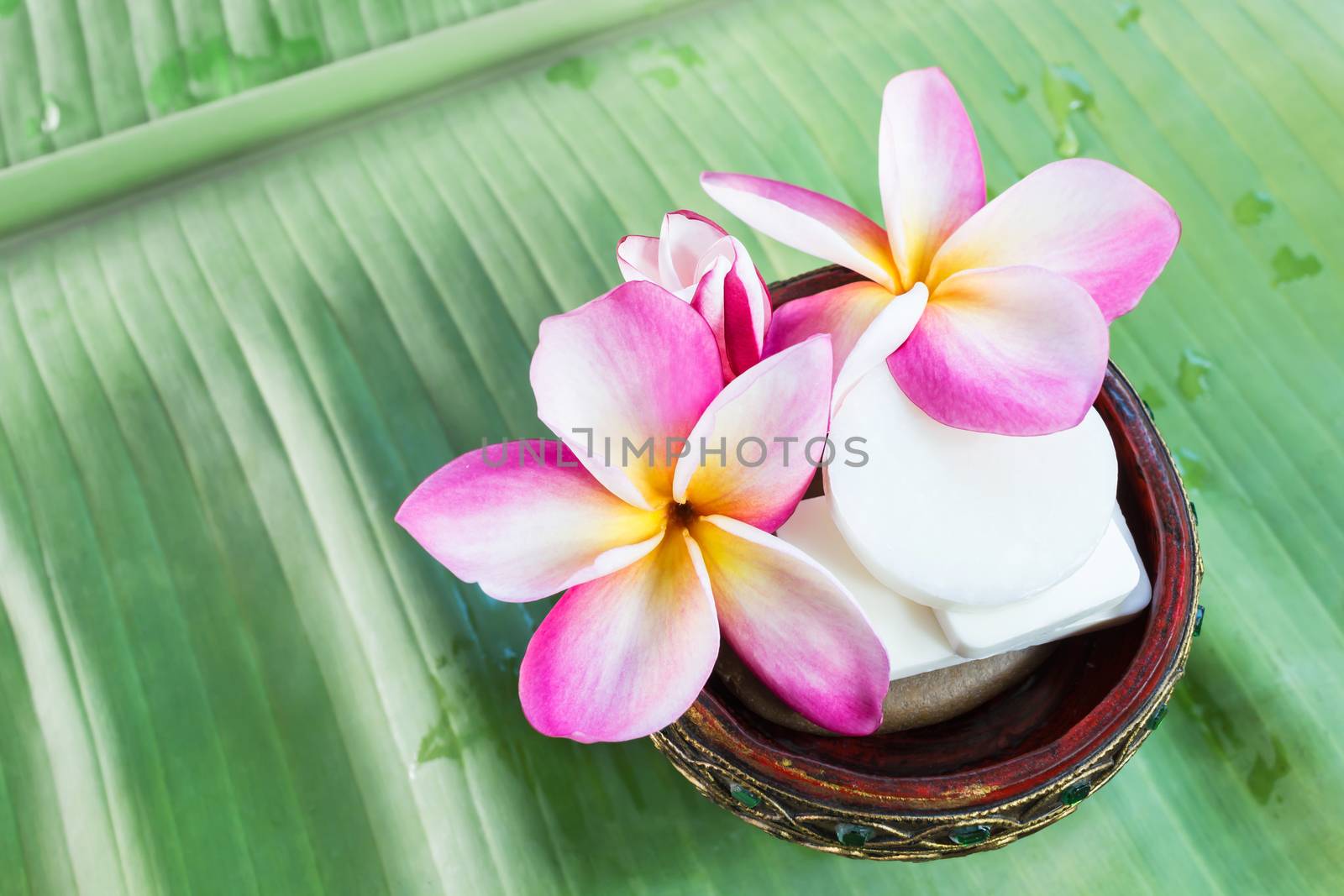Mini set of shower bath soap with flowers frangipani on green banana leaf