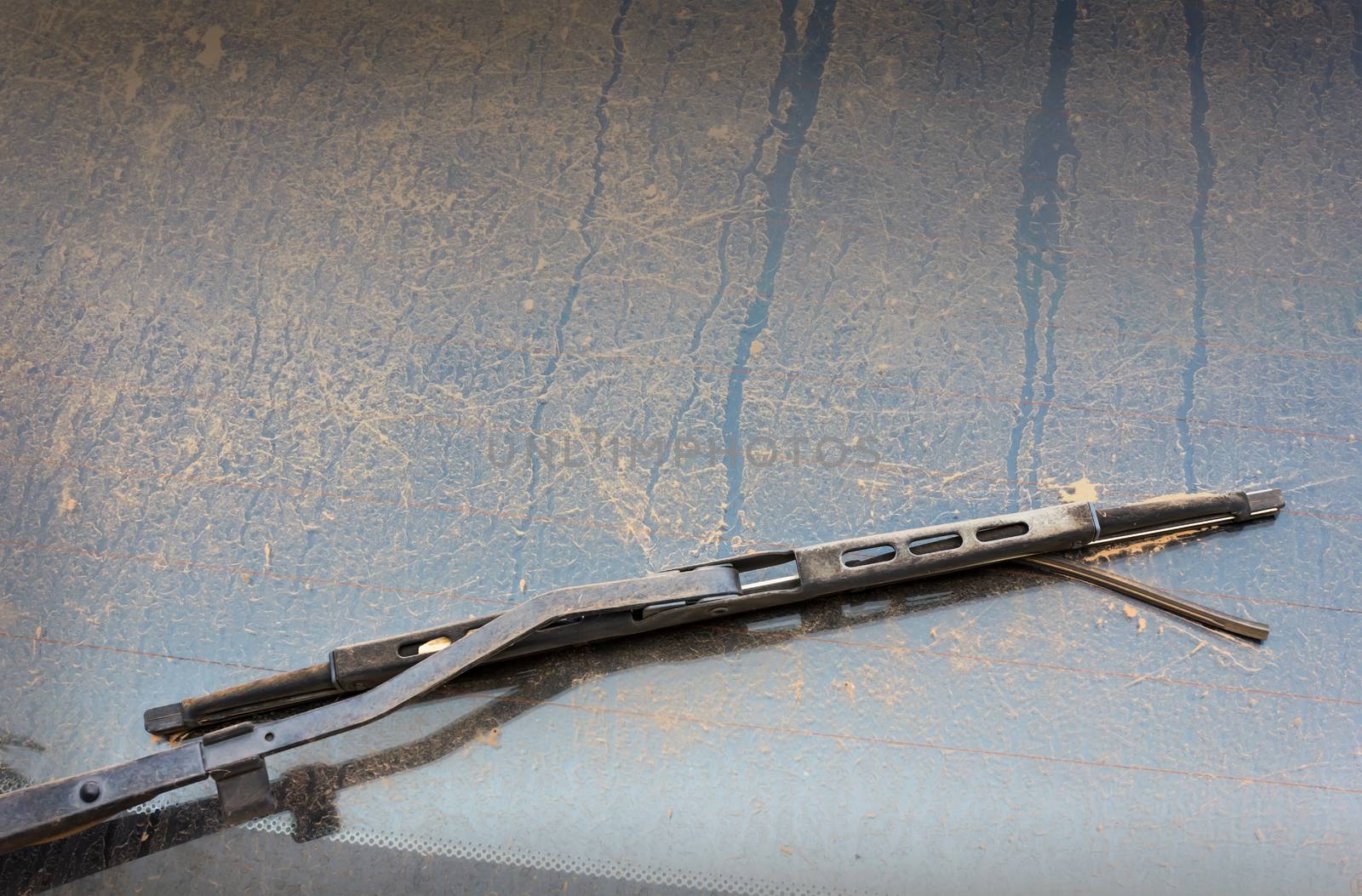 Old windshield wiper and mirror covered by dust, dirty car