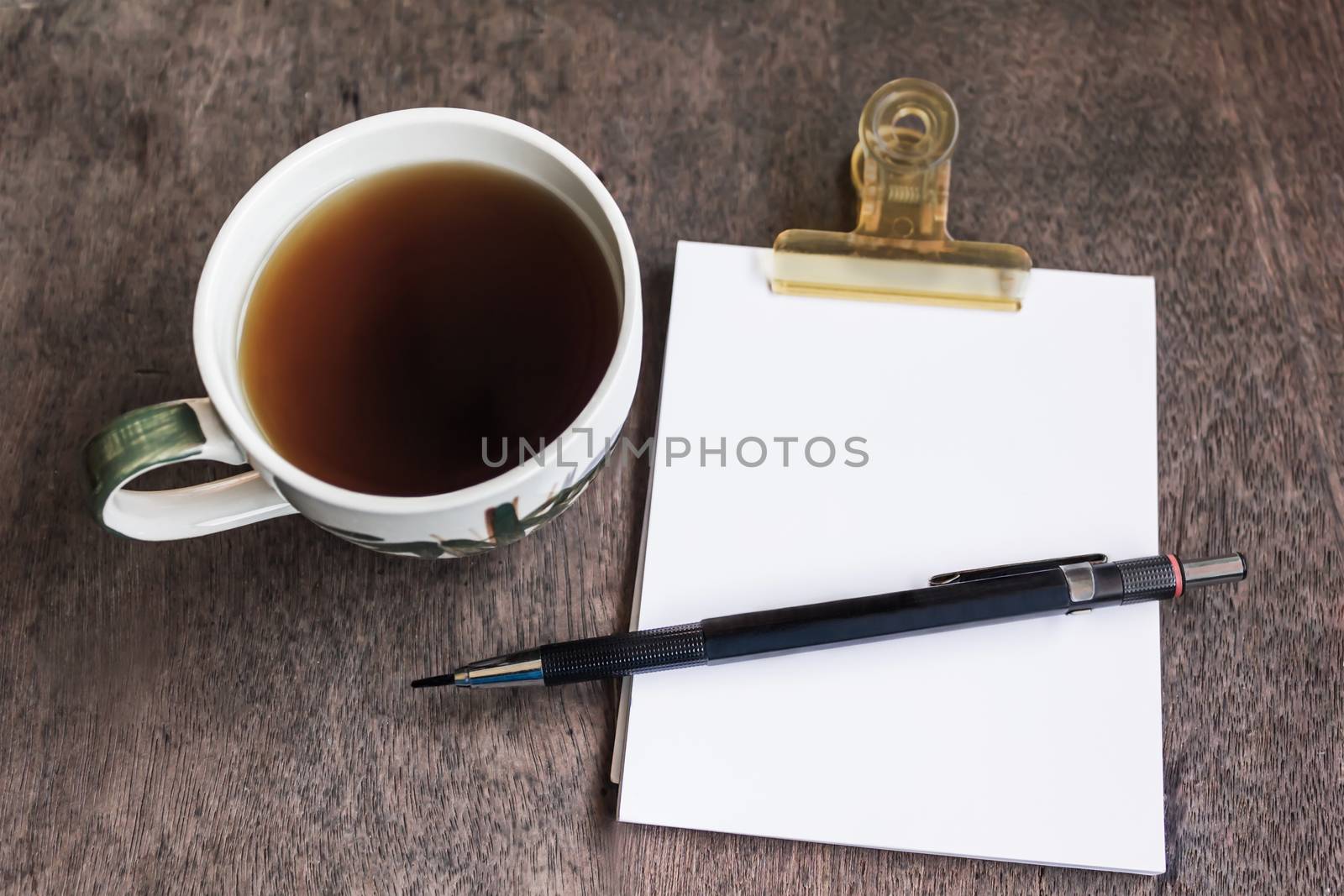 White cup of black coffee with note and pencil on wood table