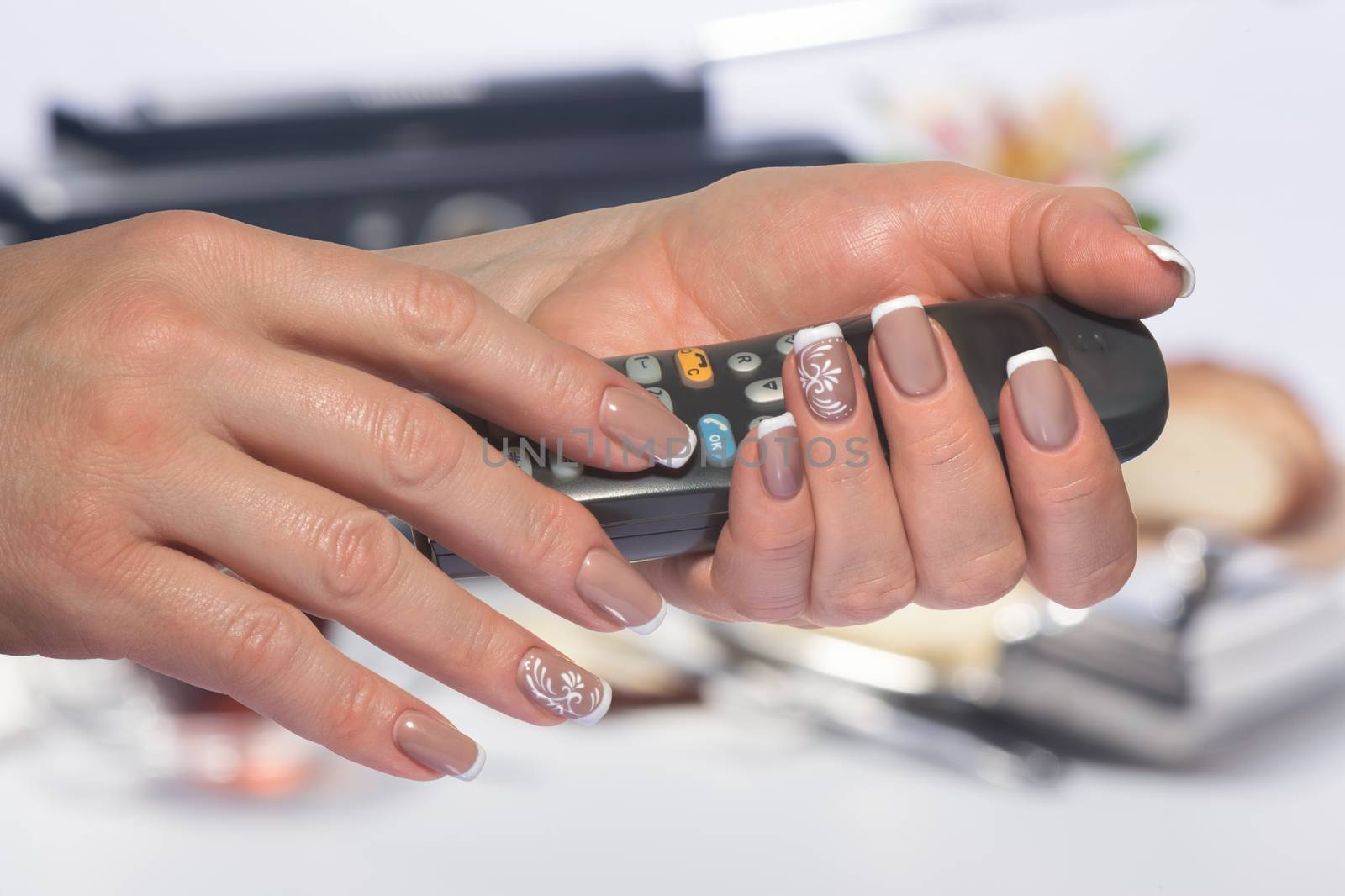 Female hands with classical French manicure hold the handset