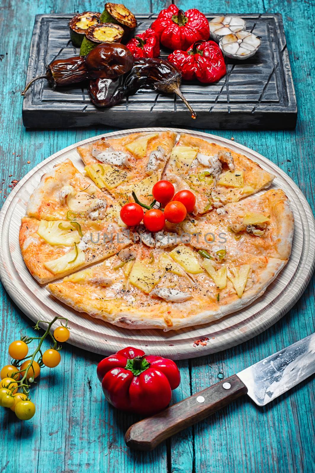 Dining table with pizza and roasted vegetables on stylish cutting board