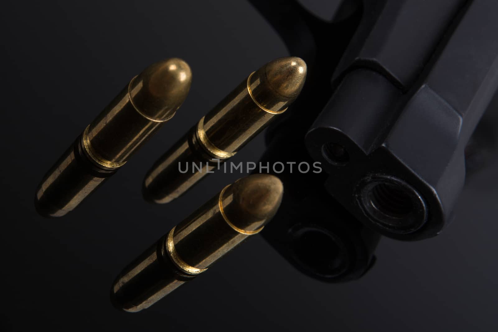 Gold bullets and gun on black background
