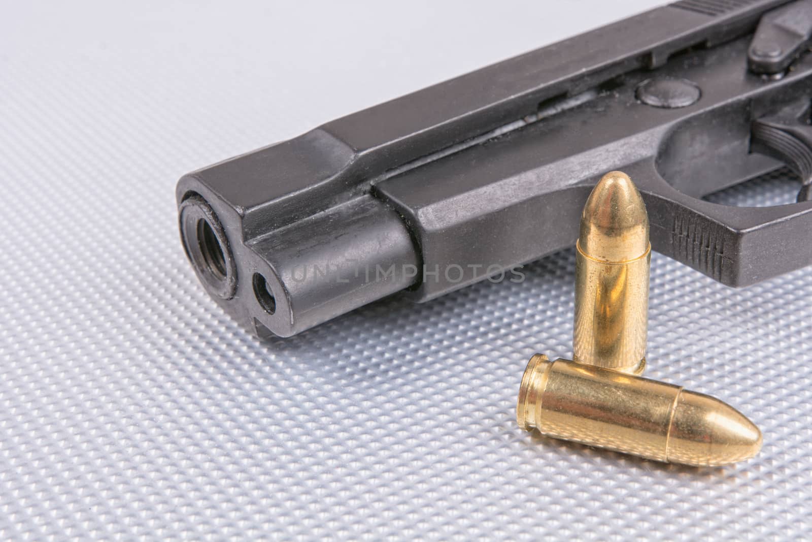 Gold bullets and gun on aluminium background