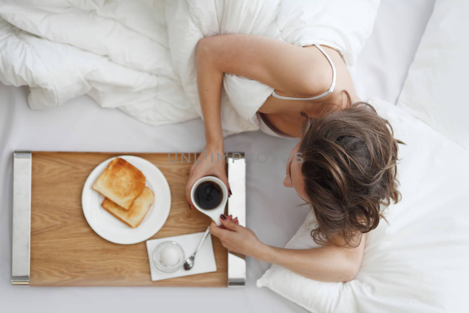 Woman having breakfast in bed by ALotOfPeople