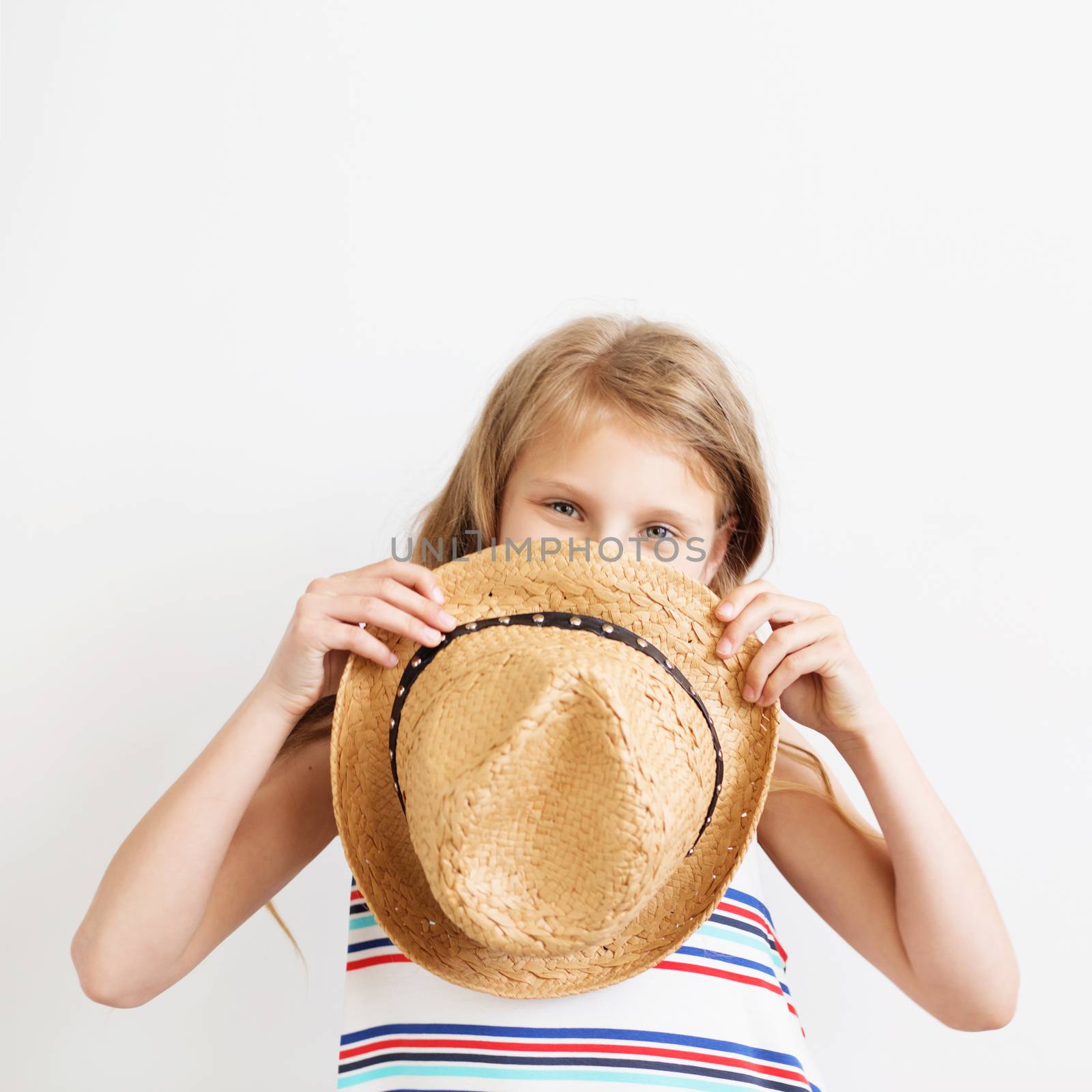 Lovely little girl with straw hat against a white background. Happy kids