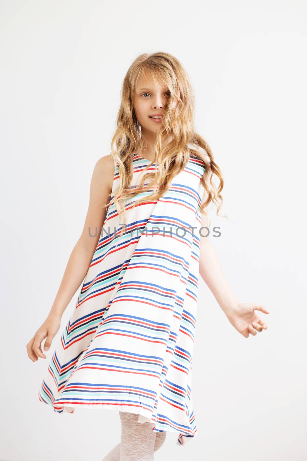 Lovely little girl in a striped dress against a white background. Happy kids