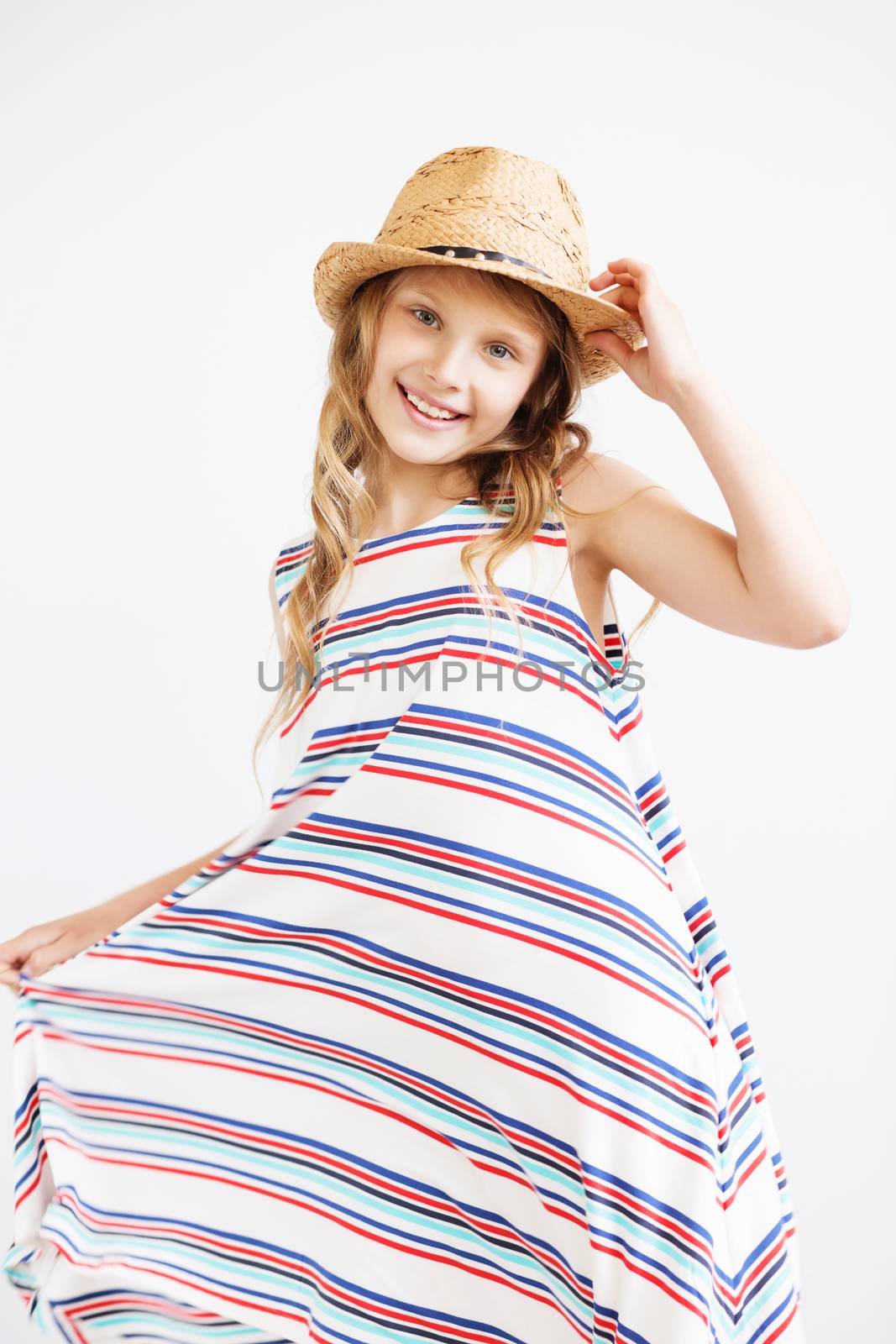 Lovely little girl in straw hat against a white background. Smiling summer kids