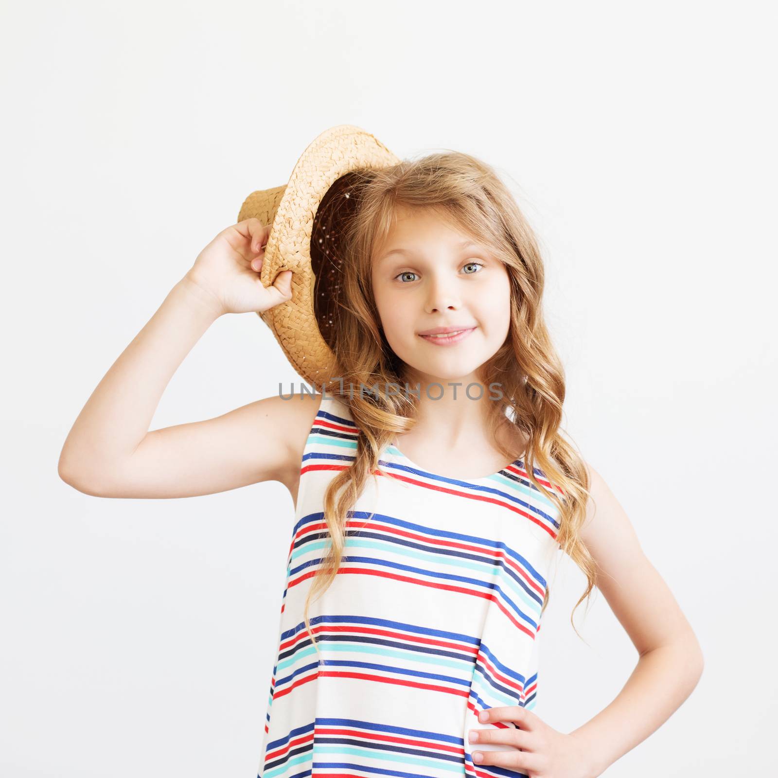 Lovely little girl with straw hat and striped dress against a white background. Happy kids